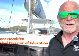 A person on a sailboat with lush islands and boats in the background, wearing green sunglasses and a NauticEd shirt.